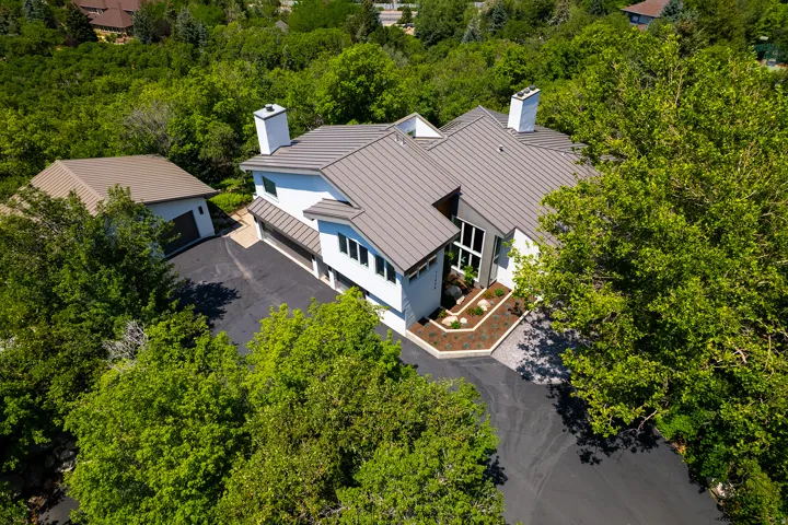 Contemporary architecture featuring a multi-level roofline, extensive windows, an attached two-car garage, a separate detached garage, and a landscaped entry