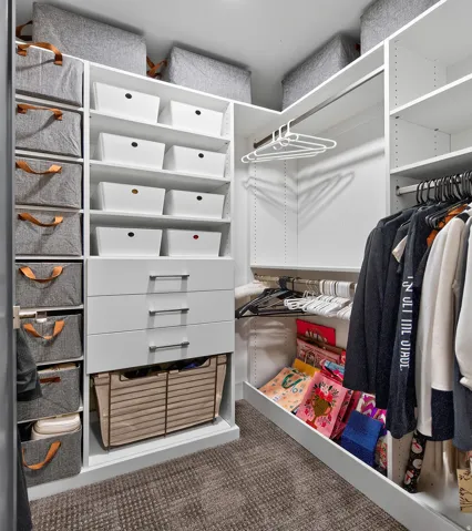 White built-in closet system featuring multiple shelves, drawers with brushed nickel pulls, and hanging rods