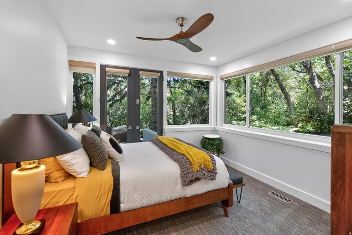 Recessed lighting, wood-finish ceiling fan, full-light French doors, expansive transom windows, and light gray carpeting