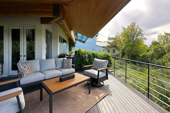 Expansive outdoor deck with wood-finish ceiling, double glass-paneled doors, and contemporary metal railing