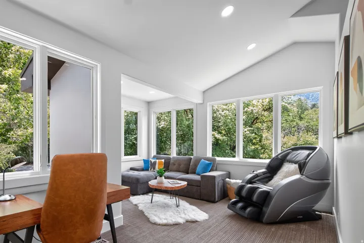 Vaulted ceiling, recessed lighting, multiple large windows, and wall-mounted art
