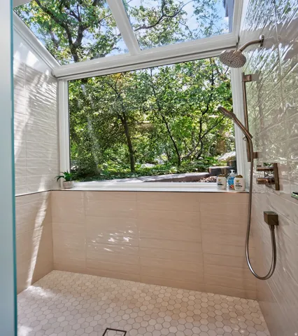 Glass-enclosed shower with a large fixed window, overhead skylight, and hexagonal tile flooring