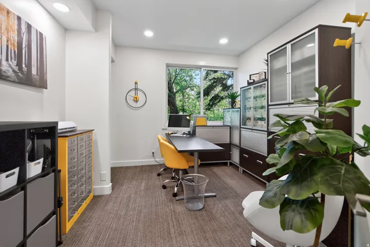 Recessed lighting illuminates this bright room featuring a large window, textured carpeting, and built-in cabinetry