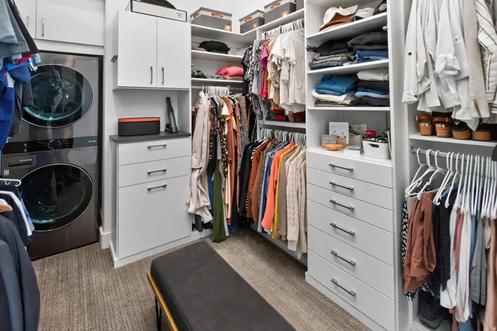 Integrated laundry appliances, custom built-in cabinetry, extensive hanging storage, multiple shelving units, and drawer storage