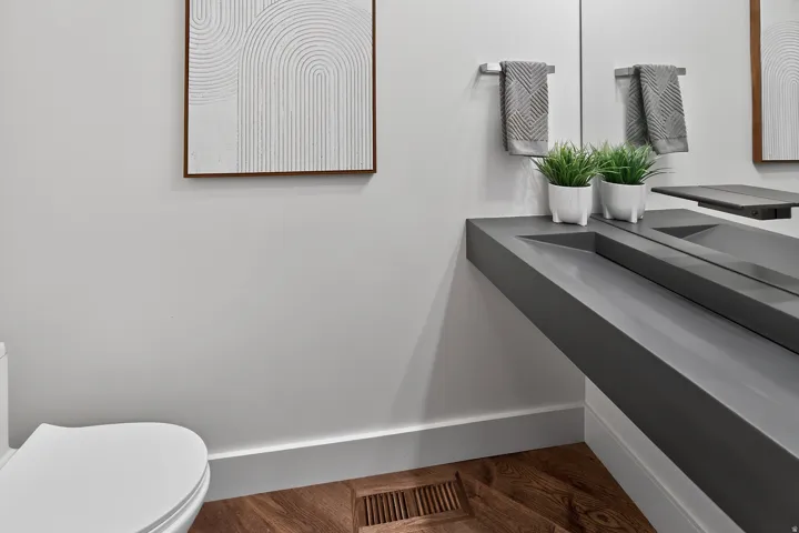 Floating vanity with integrated basin, wall-mounted faucet, and wood-finish flooring