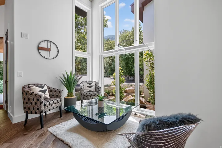 Floor-to-ceiling windows, wood-finish flooring, white walls, and a recessed ceiling light fixture