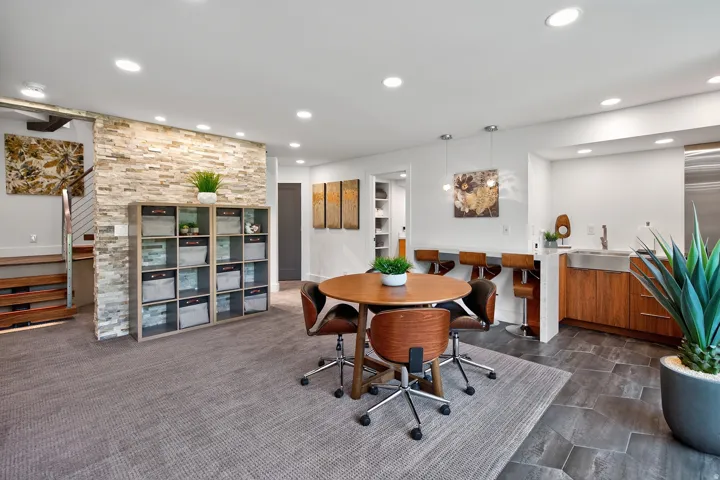 Recessed lighting illuminates the space, featuring a stone accent wall, wood-finish cabinetry, and a large farmhouse-style sink
