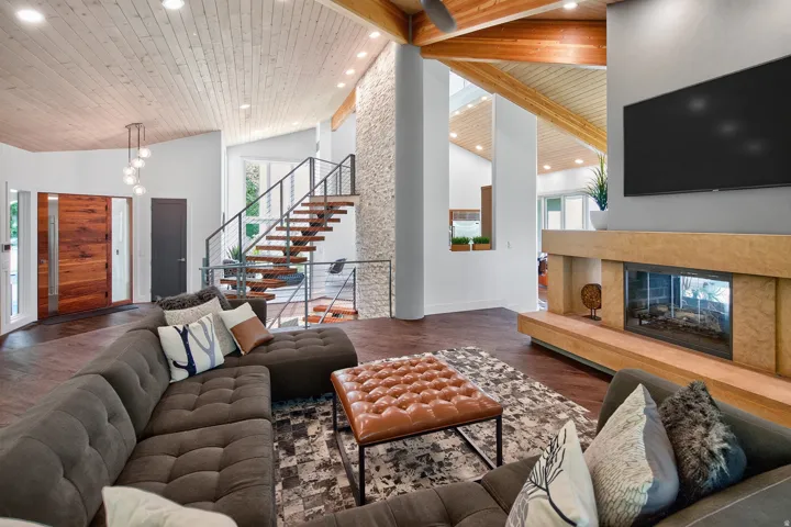 Vaulted wood-paneled ceilings, wood-finish flooring, a stone-clad fireplace with a hearth, and an open-tread staircase with metal railings