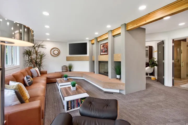 Recessed lighting illuminates a spacious living area featuring a built-in fireplace with a stone surround and hearth