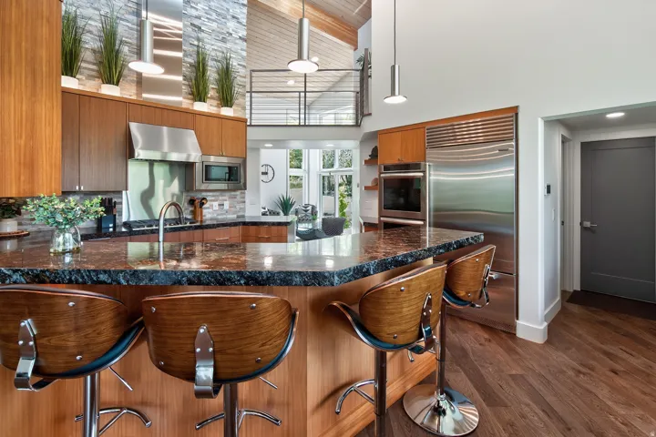 Gourmet kitchen featuring a large island, stainless steel appliances, wood-finish cabinetry, and high ceilings