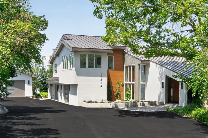Modern exterior featuring multiple rooflines, a wood-paneled accent wall, and a separate garage structure
