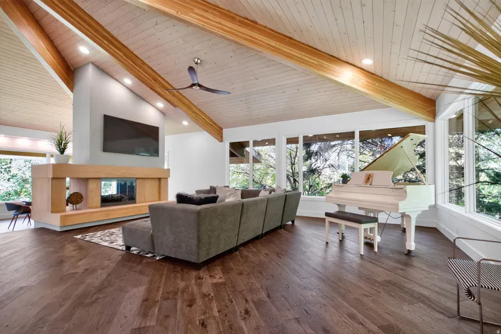 Vaulted wood-paneled ceiling with exposed beams, recessed lighting, wood-finish flooring, a contemporary fireplace with a built-in mantel, and large windows
