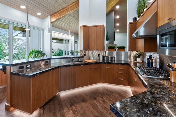 Wood-finish flooring with under-cabinet lighting, dark stone countertops, stainless steel appliances, wood-finish cabinetry, and a gas cooktop