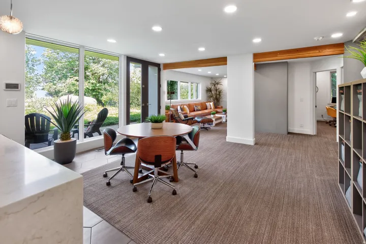 Expansive floor-to-ceiling windows, wood support beams, recessed lighting, and a large sliding door