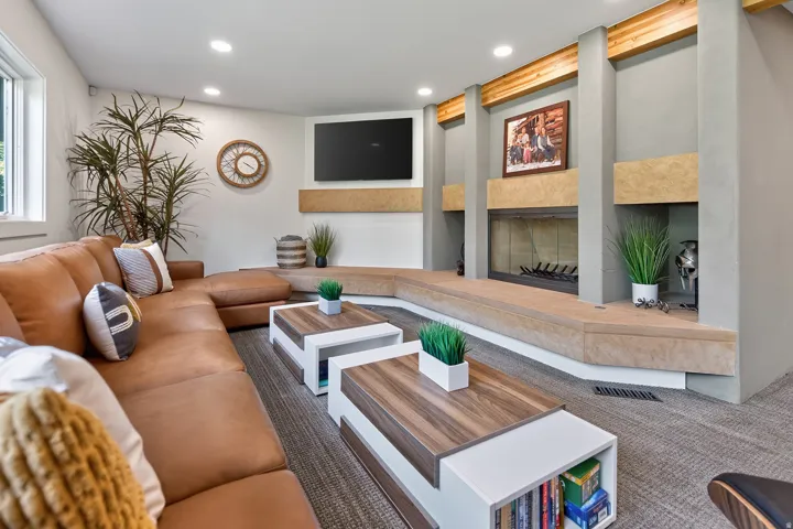 Recessed lighting illuminates the living area, featuring a built-in fireplace with a stone hearth and integrated shelving
