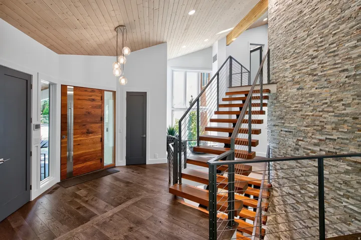 Hardwood flooring throughout, a wood-paneled ceiling, and a modern chandelier
