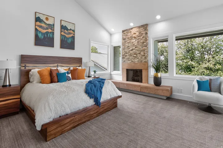 Vaulted ceiling, stone-clad fireplace with hearth, recessed lighting, large windows, and neutral carpeting