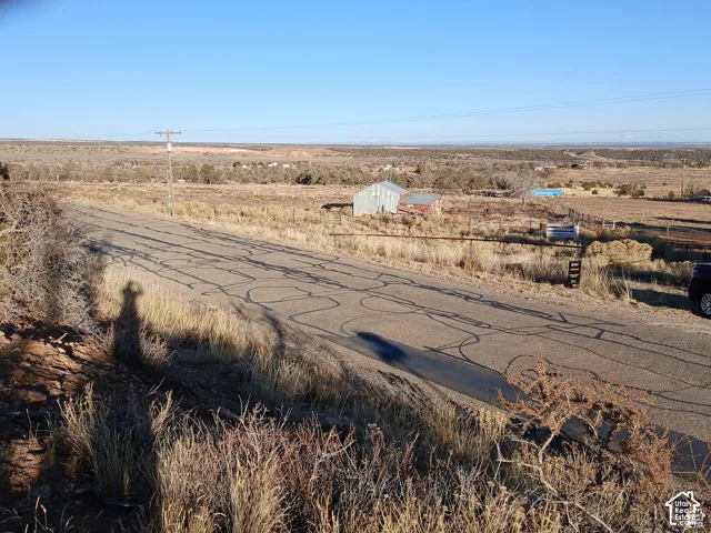 Expansive desert landscape with a paved road, open terrain, and distant structures