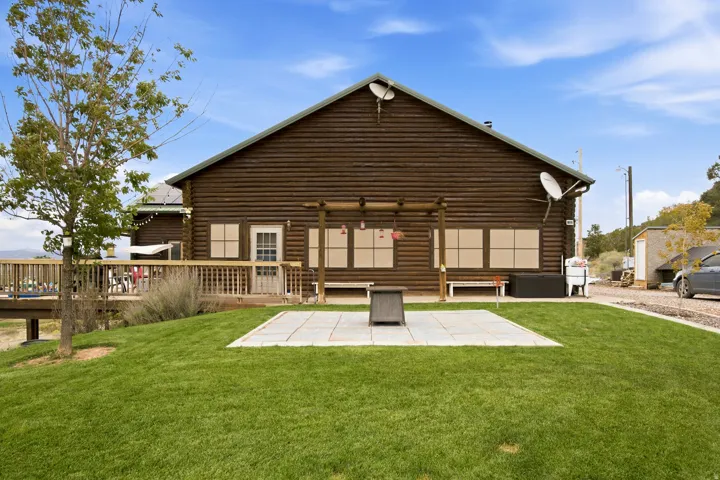 Log-sided exterior with a pitched roofline, accompanied by a spacious elevated deck and a ground-level patio