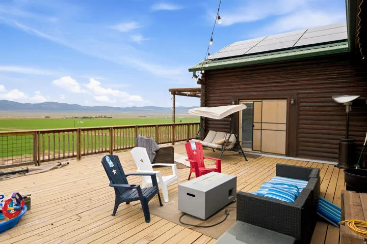 Expansive outdoor deck with wood railing, log-style exterior, sliding glass doors, and solar panels