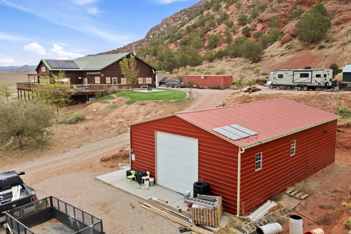 Red corrugated metal shed with a white roll-up door and solar panels