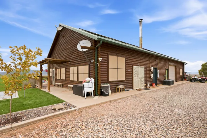 Log siding exterior with a metal roof and a gravel driveway