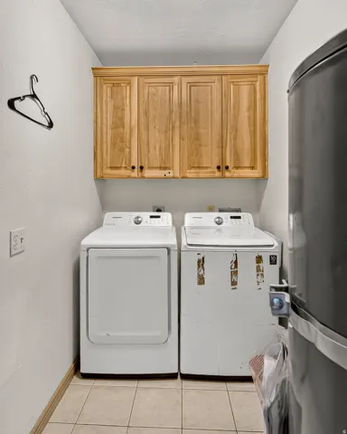 Built-in wood-finish cabinetry, tile flooring, and dedicated laundry appliances