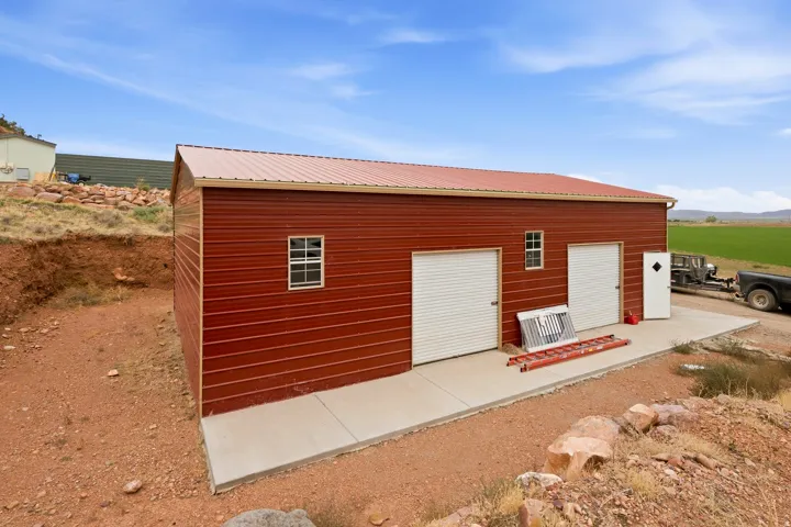Red metal siding, metal roof, two roll-up garage doors, single exterior door, and a concrete pad