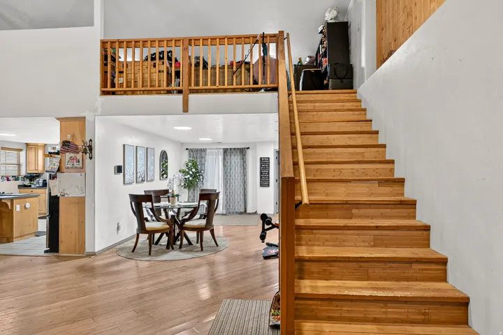 Wood-finish flooring throughout, with a wood staircase and railing leading to an open loft