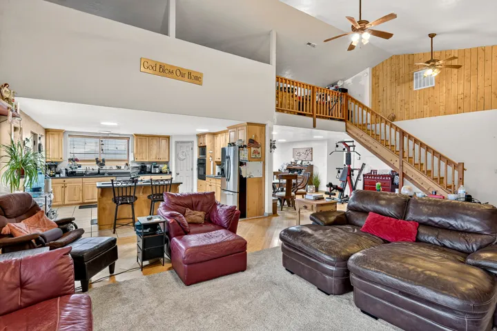 Vaulted ceiling, wood-finish flooring, wood-paneled accents, built-in kitchen cabinetry, and a central kitchen island with seating
