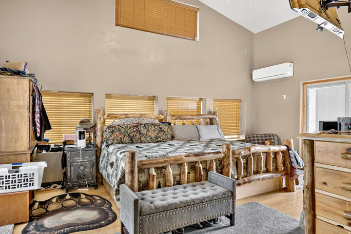 Vaulted ceilings, wood-finish flooring, and multiple windows with blinds