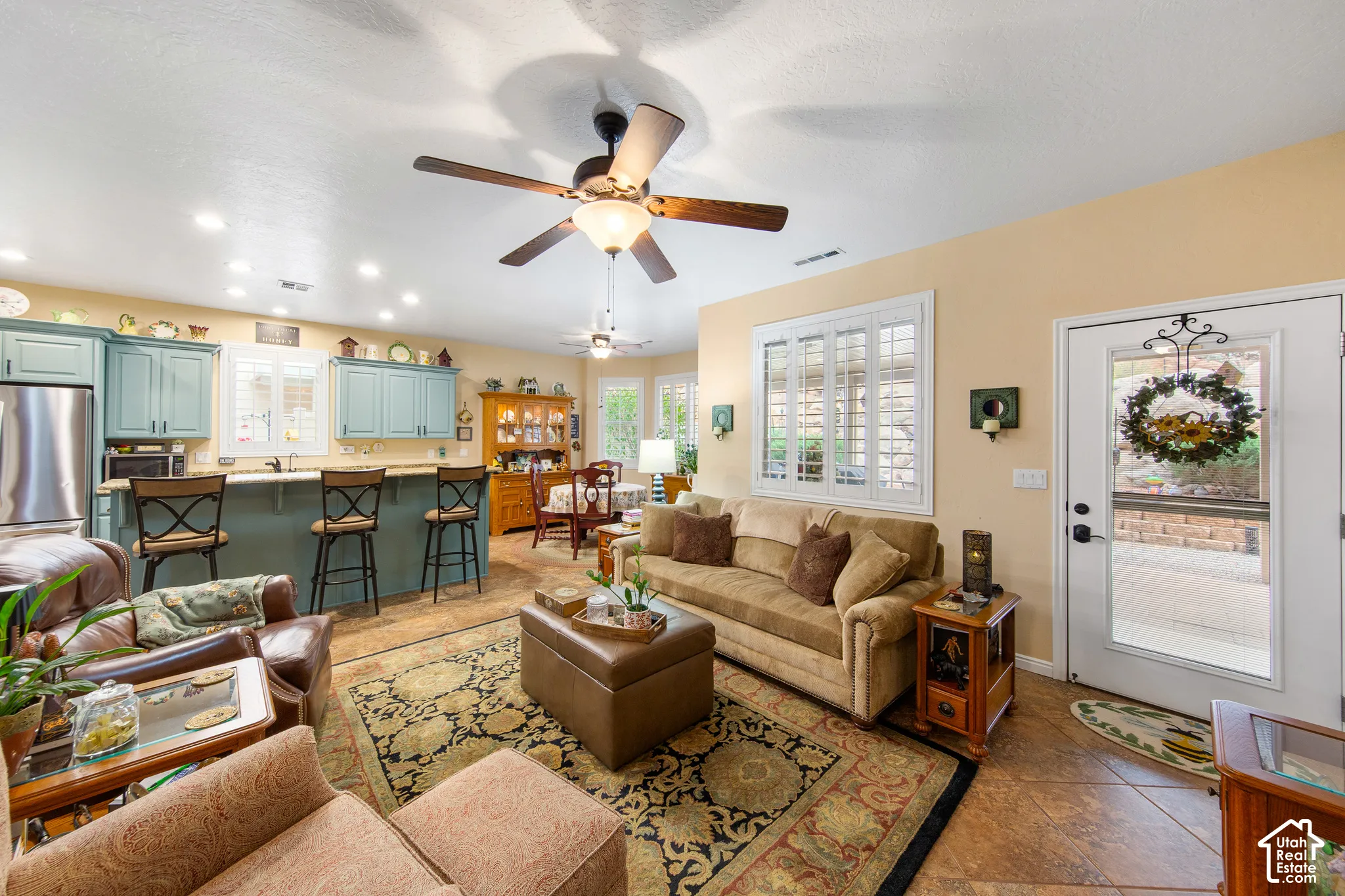 Open-concept living space featuring a kitchen with blue cabinetry, a breakfast bar, and stainless steel appliances