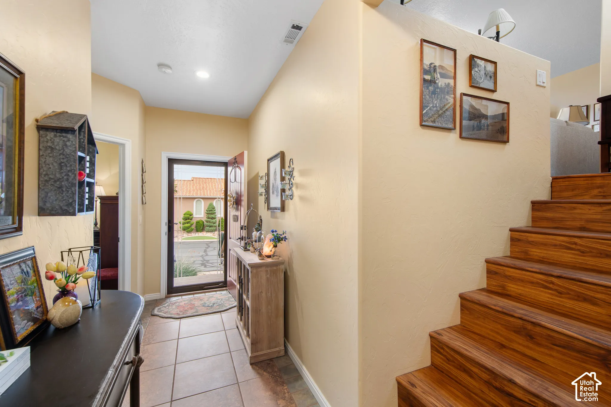 Entryway featuring tile flooring, a clear glass door with sidelight, and wood-finish stairs