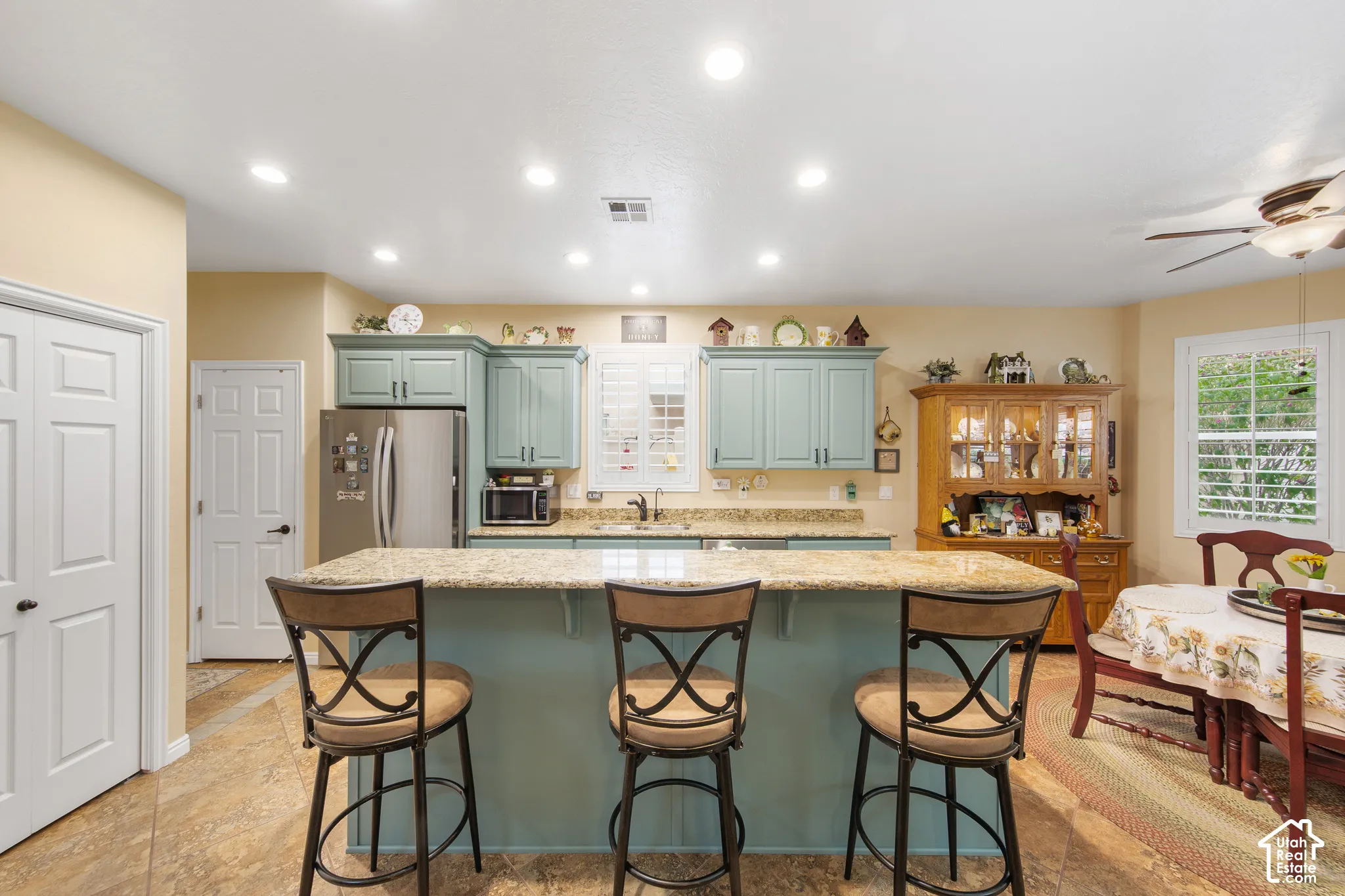 Kitchen featuring a central island with countertop seating, recessed lighting, stainless steel refrigerator, and light blue cabinetry