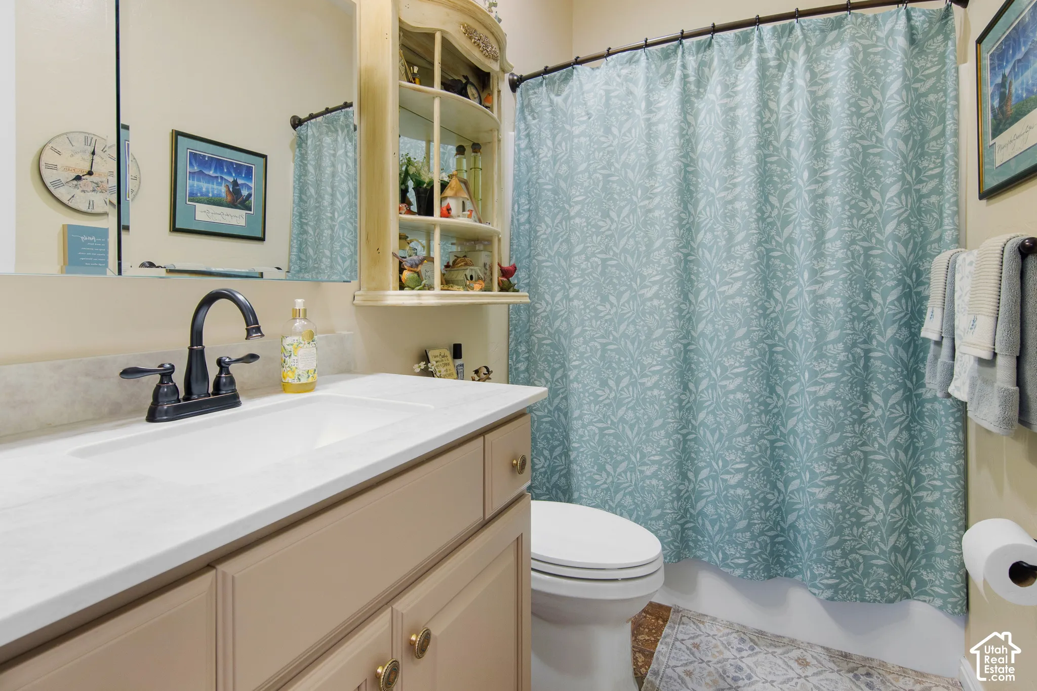 Bathroom vanity with a white countertop and integrated sink, bronze-finish faucet, and built-in storage shelving