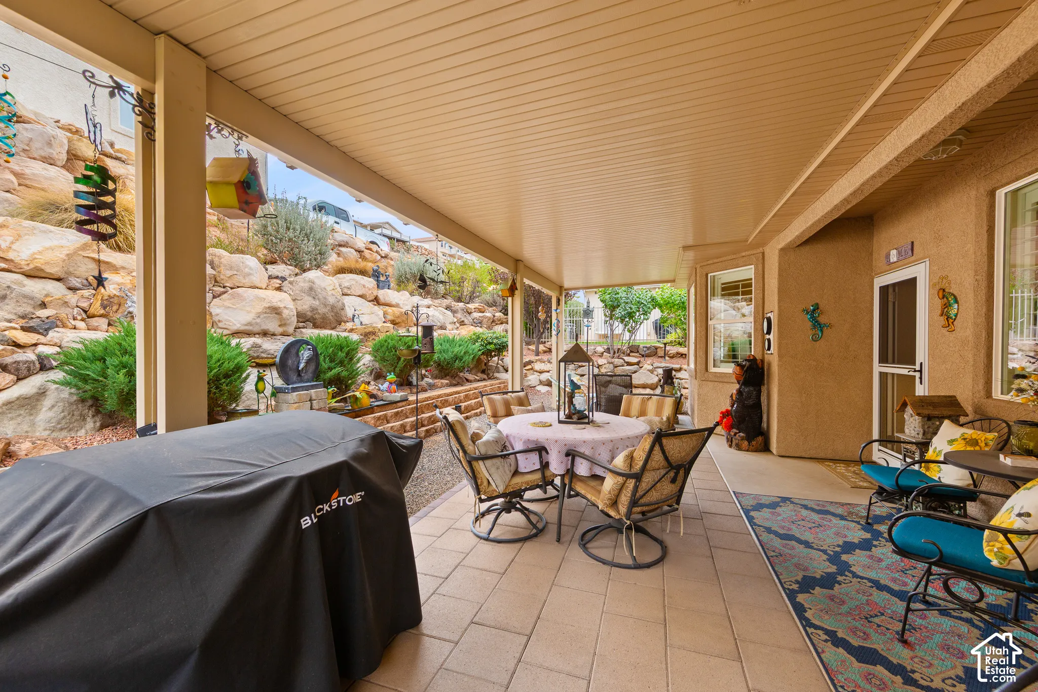 Covered patio with recessed lighting, integrated stucco exterior, paver flooring, and terraced landscaping