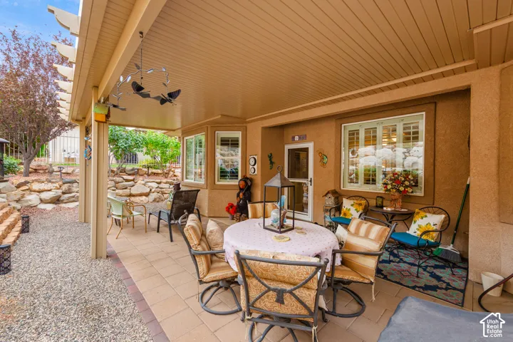 Covered patio with a slatted ceiling, paver flooring, stucco exterior, and multi-pane windows