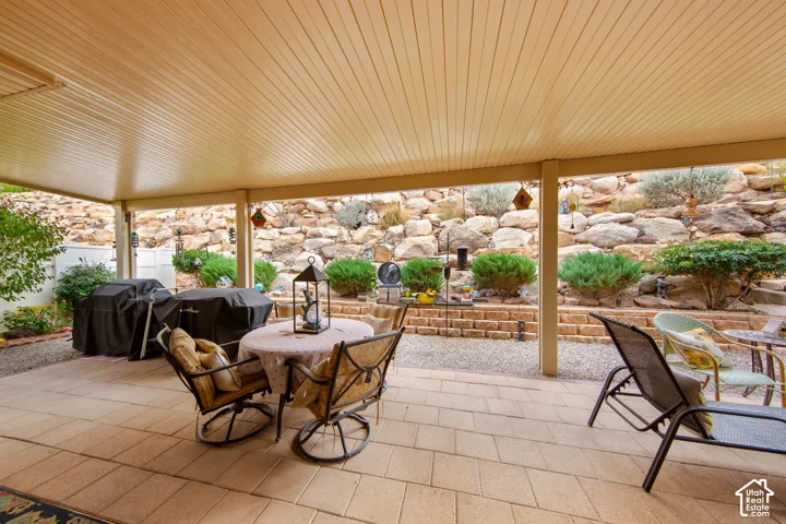 Covered patio with a stone-finish tile floor, an overhead ceiling, and a tiered rock landscaping feature