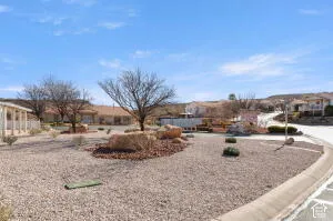 Low-maintenance xeriscaped lot featuring decorative rock ground cover, natural boulder accents, mature trees, and concrete curb edging