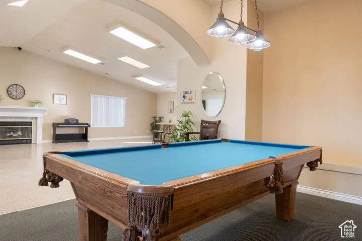 Open-concept interior featuring vaulted ceilings, a fireplace with a mantel, recessed lighting, a three-light pendant fixture, and a decorative arched wall opening