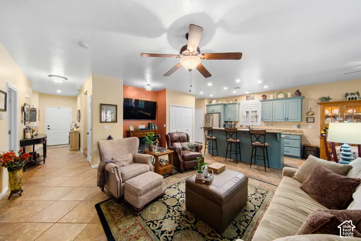 Open concept living area with ceiling fan and recessed lighting, featuring wood-finish flooring, a kitchen island with seating, and light blue cabinetry