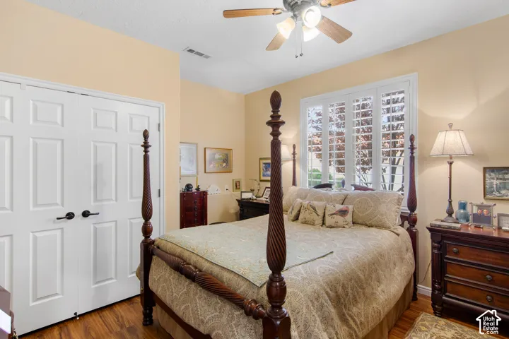 Wood-finish flooring, white paneled double doors, ceiling fan, and window with white shutters