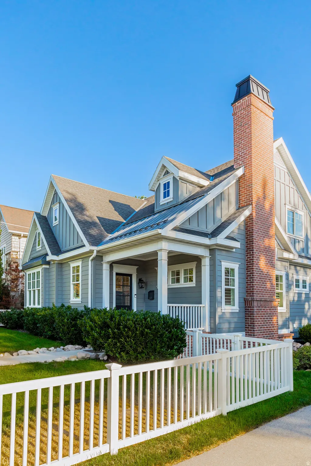 Craftsman-style exterior with gray siding, white trim, a covered front porch, and a prominent brick chimney