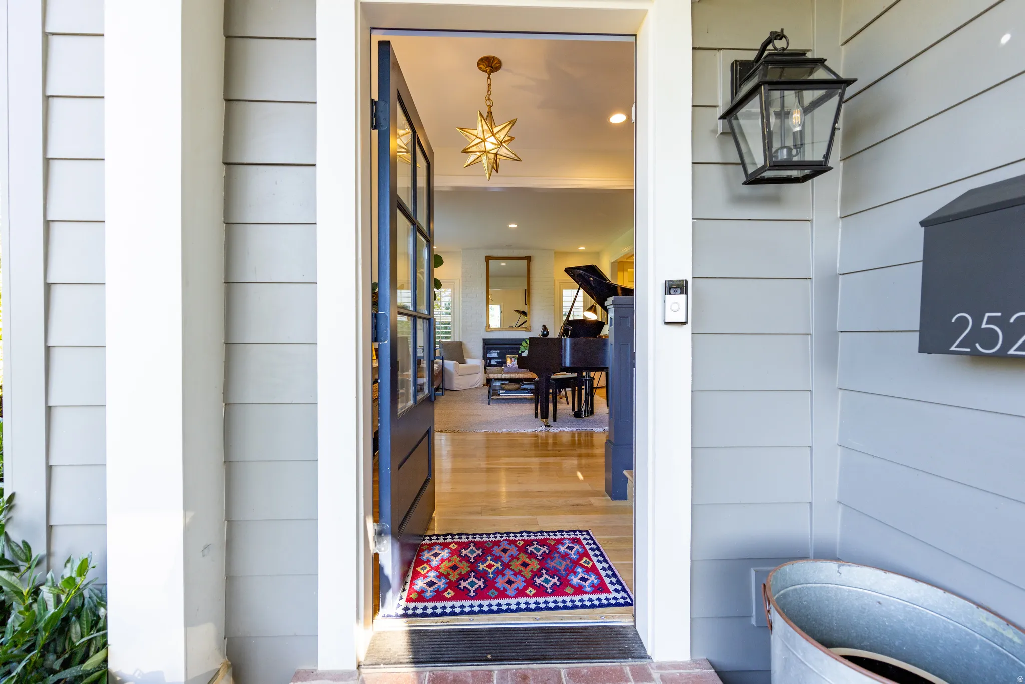 Panel siding exterior with a prominent wall lantern, house number 252, and a glass-paneled entry door