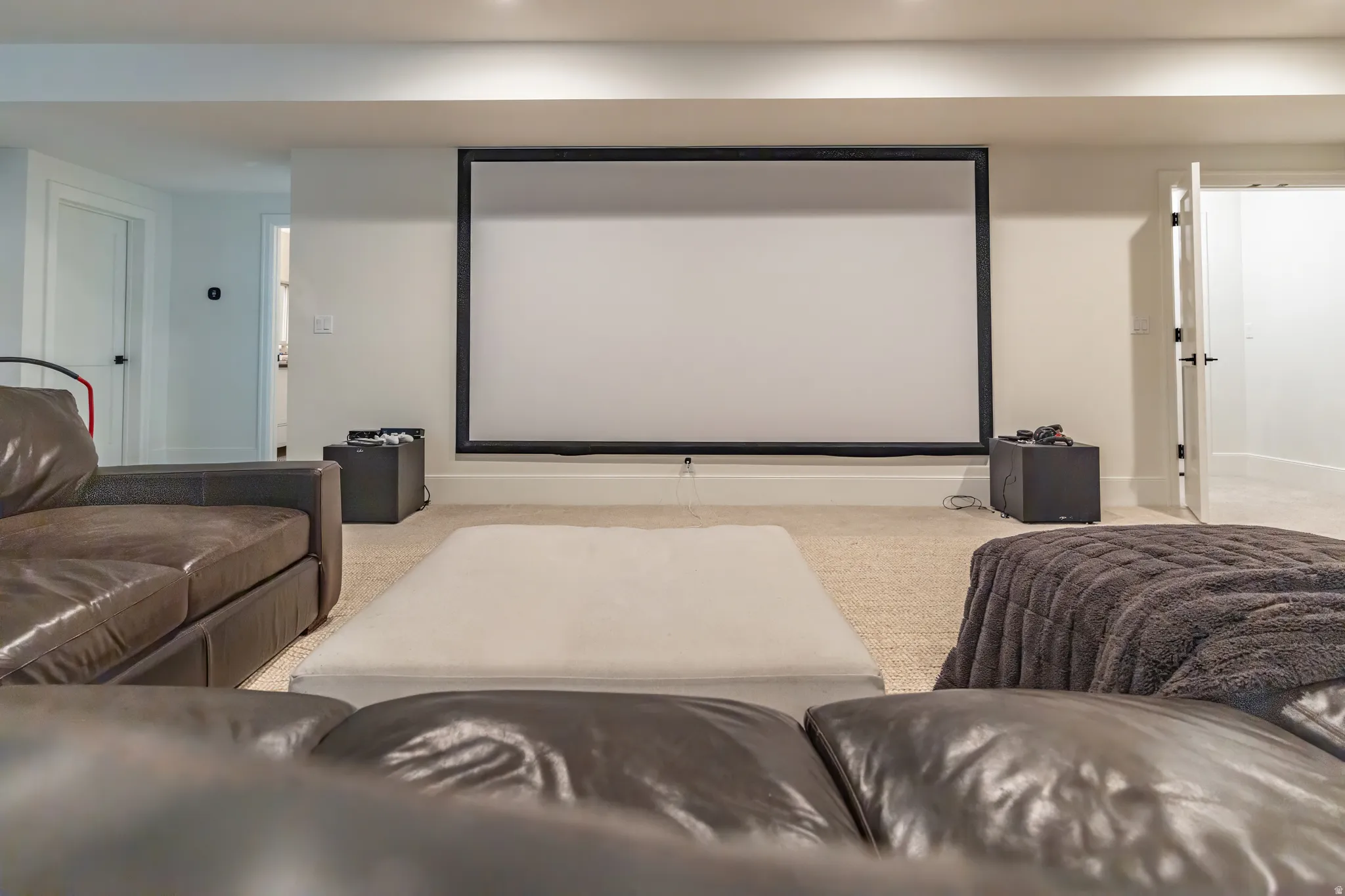 Recessed lighting, light-colored carpeting, white interior doors, and a large projection screen