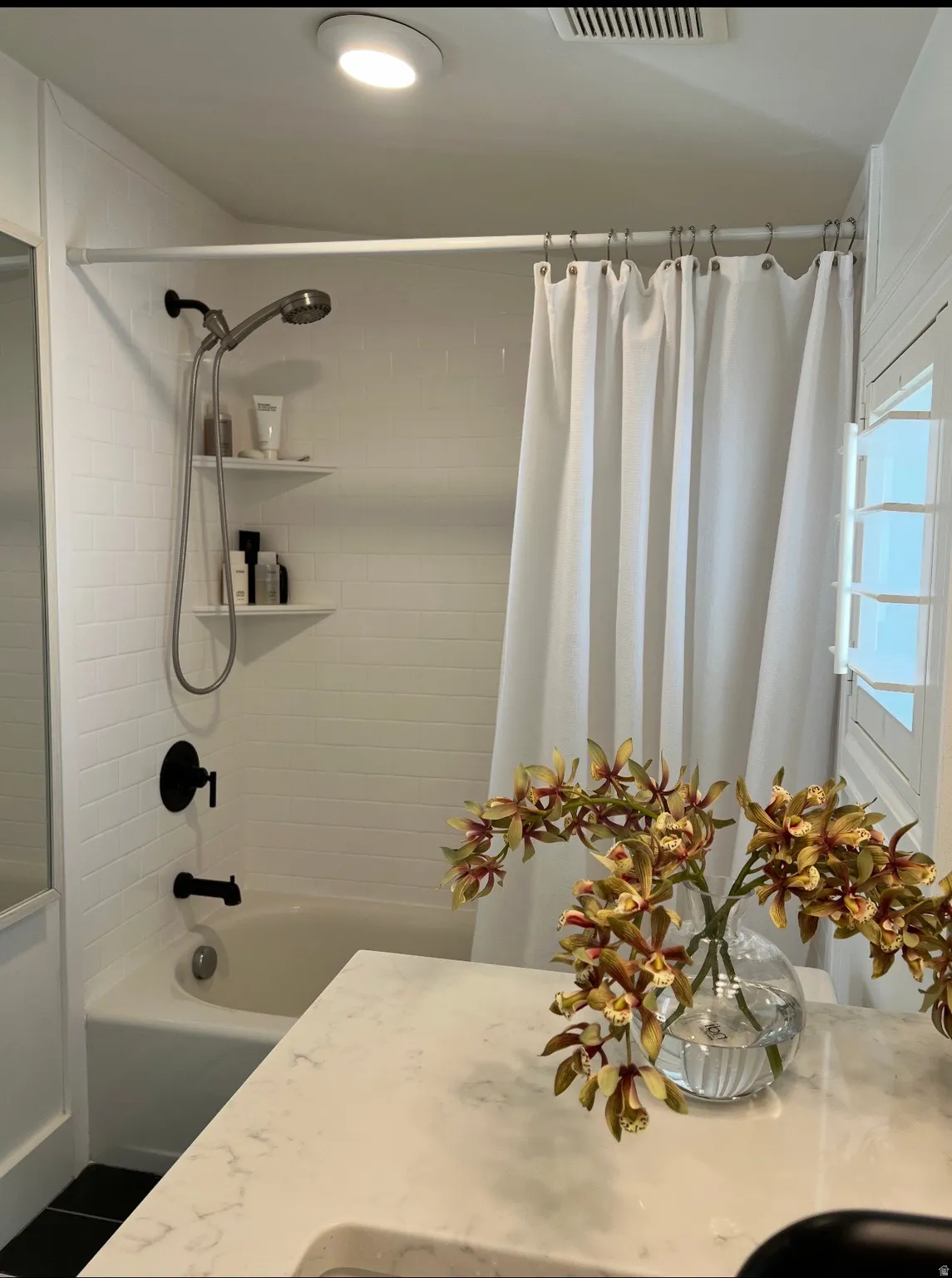 Tub/shower combination with subway tile surround, matte black fixtures, and built-in shelving