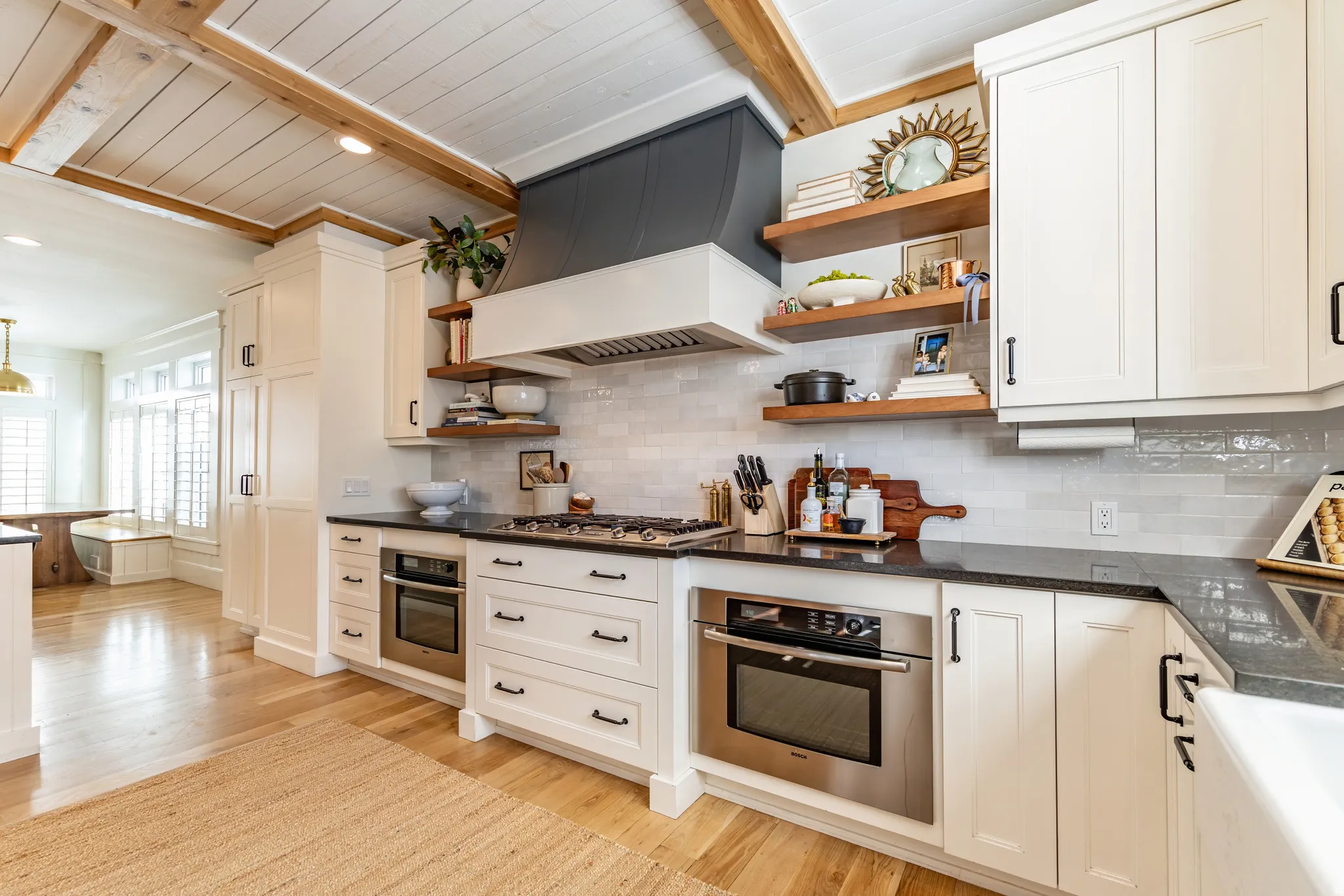 Kitchen featuring white cabinetry, dark countertops, a tile backsplash, stainless steel appliances, and wood-finish flooring