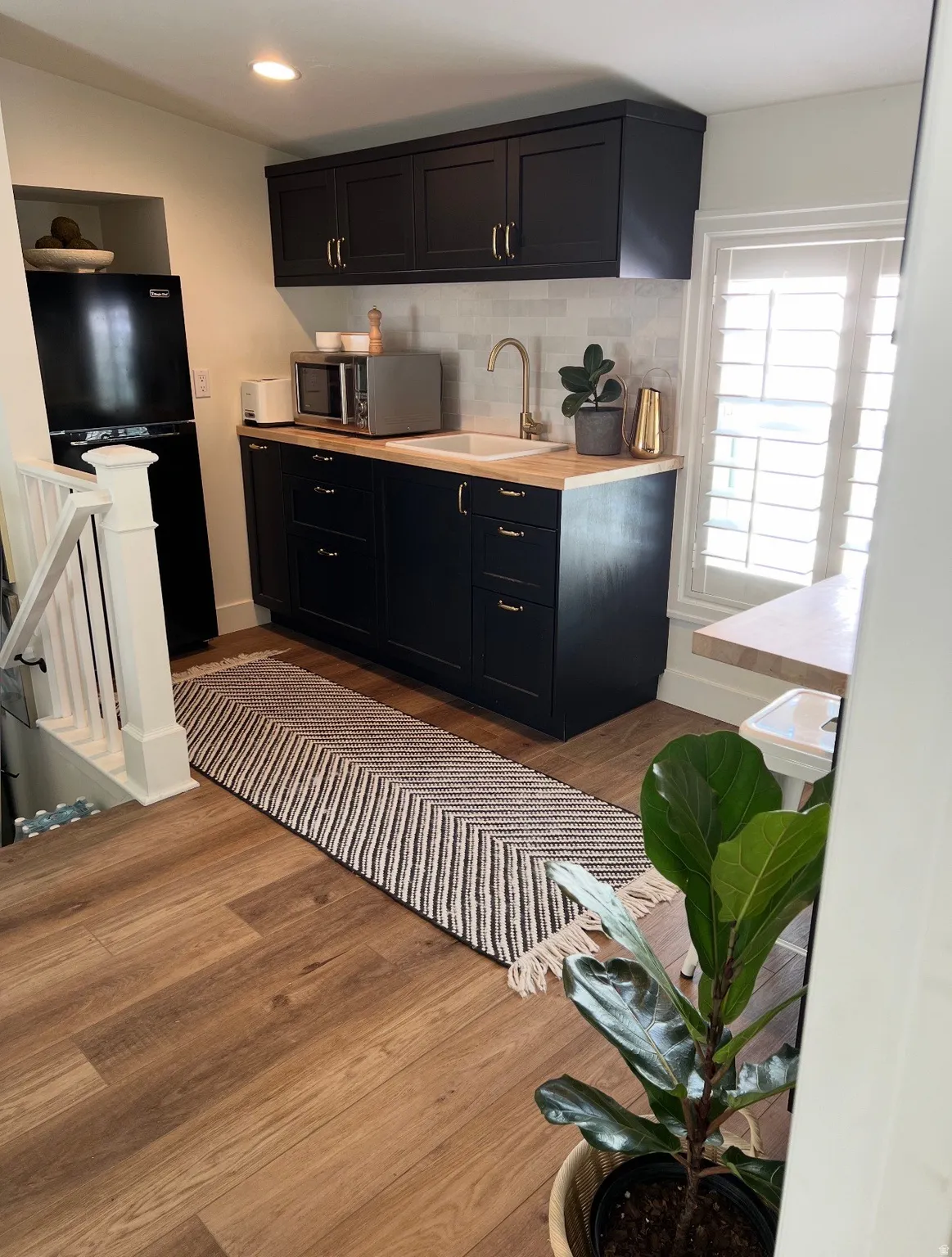 Compact kitchen featuring dark cabinetry, a white subway tile backsplash, and wood-finish countertops