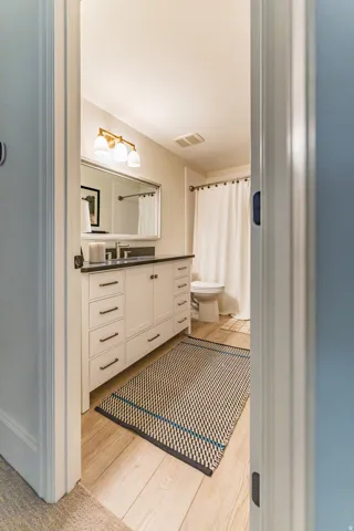 Wood-finish flooring with a white vanity featuring multiple drawers and cabinets