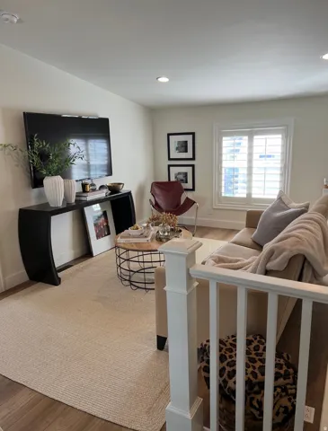Recessed lighting, wood-finish flooring, white walls, and a window with white louvered shutters